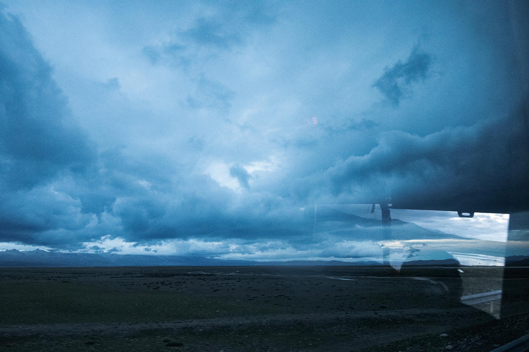 Early morning view from a bus window, with the sky filled with clouds.