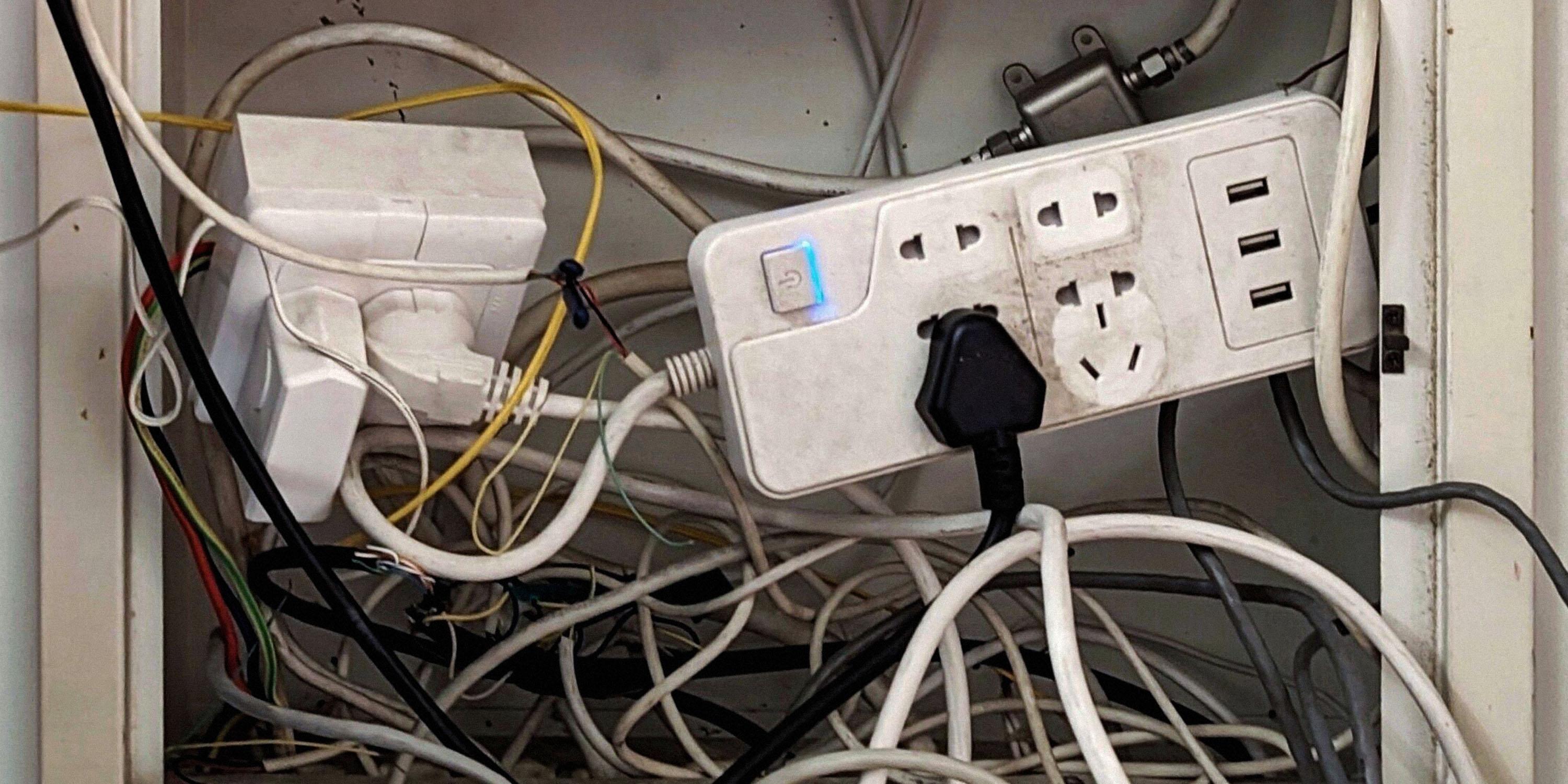An electrical outlet on a wall with multiple wires plugged in, showcasing a homelab setup.