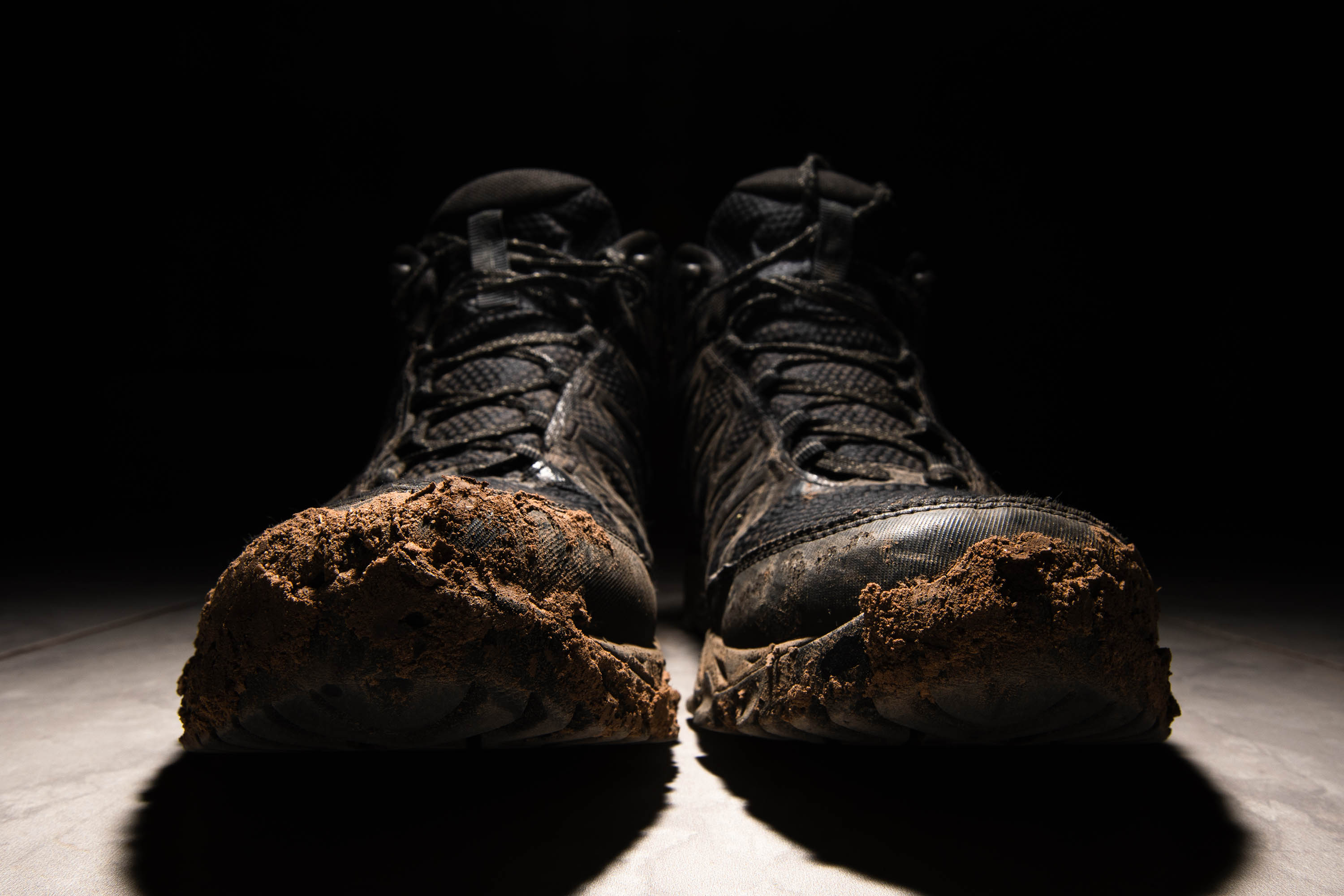 Boots covered with dirt under strong contrast lighting.